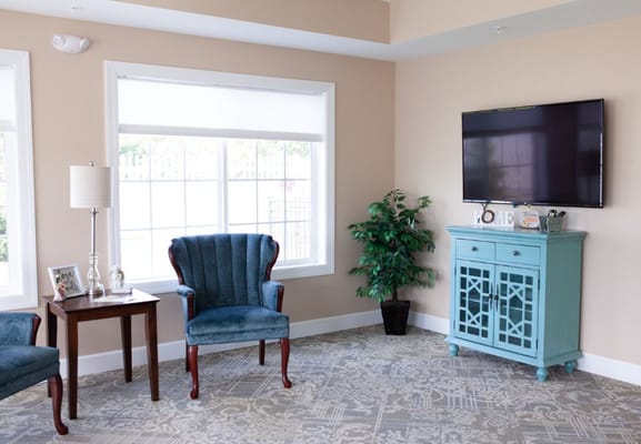 Lounge area with two blue chairs, a small table, and a TV.