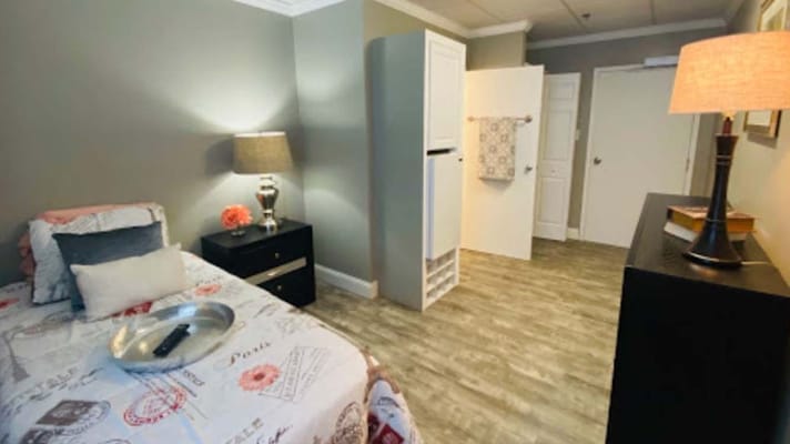 A cozy resident room with a bed and lamp