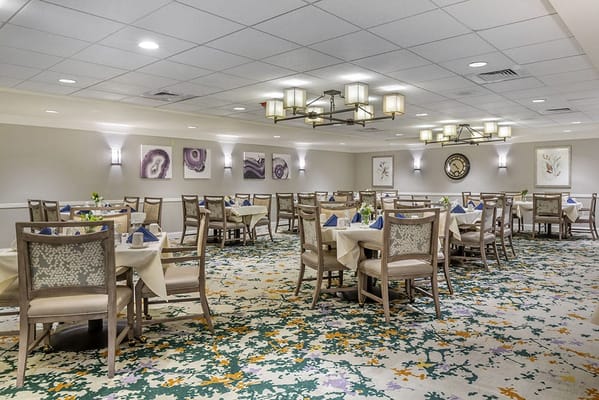 Dining room with neatly set tables and floral carpet