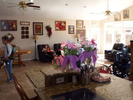 Bright common area with floral arrangements and residents engaged in activities.