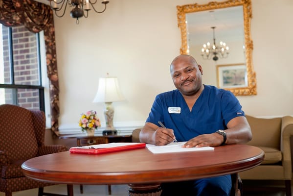 Staff member writing at a table in a common area