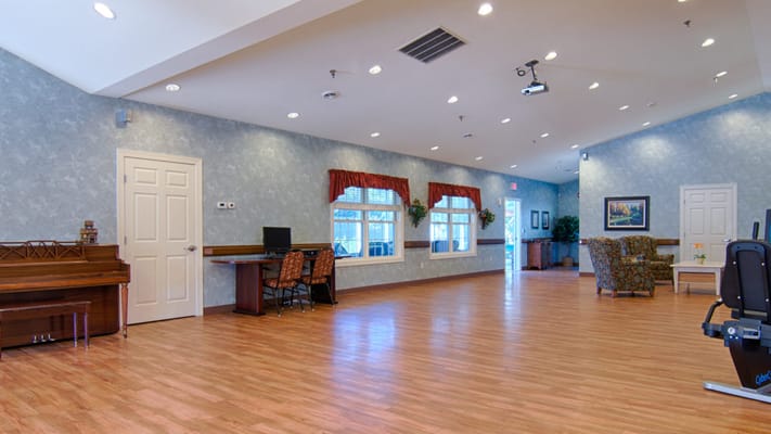Spacious common area with seating, a piano, and computer stations.
