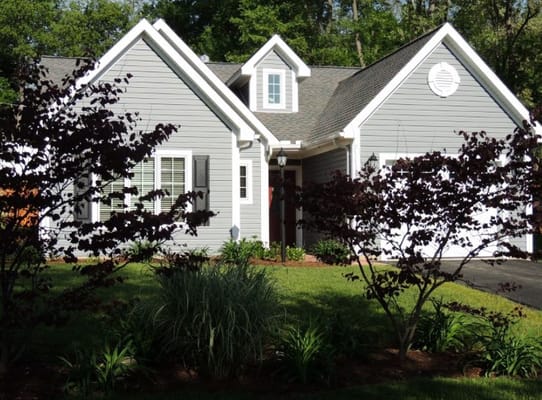 Gray cottage surrounded by greenery