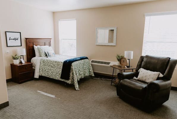 A private resident room with bed and chair