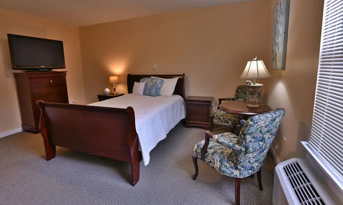 A well-furnished bedroom featuring a bed, TV, and seating area.