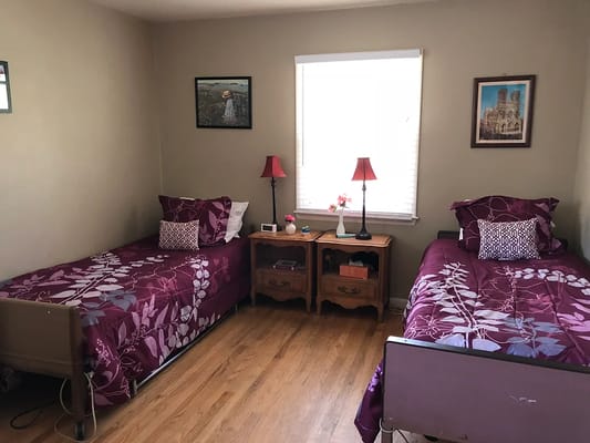 A cozy bedroom with two beds, floral bedding, and wooden furniture.