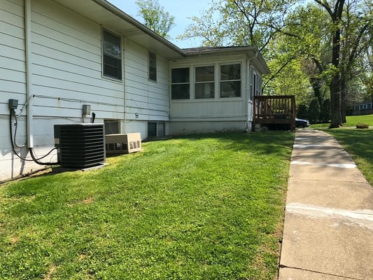Well-maintained grassy side yard of a senior living facility with air conditioning units.