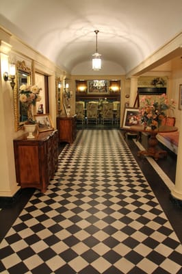 Well-decorated hallway with checkered floor and floral arrangements