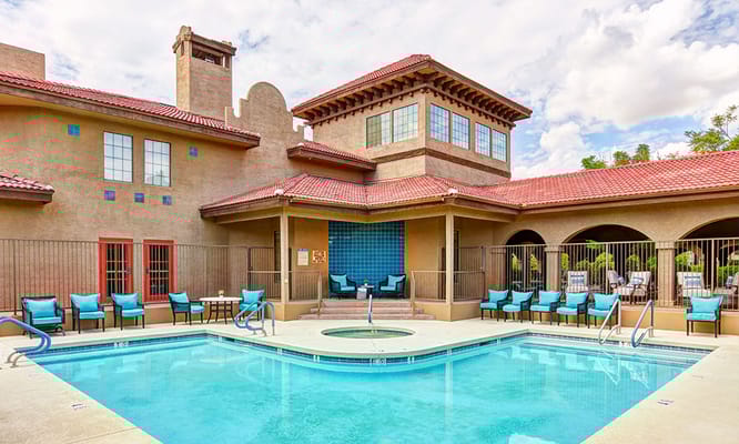 Outdoor pool area with lounge chairs and facility building