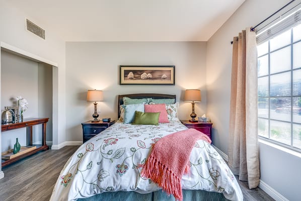 A well-decorated private resident room with a bed and natural light