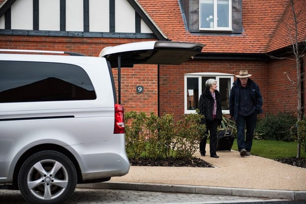 A couple leaving in front of a facility with a vehicle