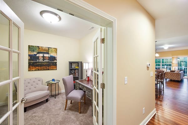 A small office space with a desk, chair, and art on the wall