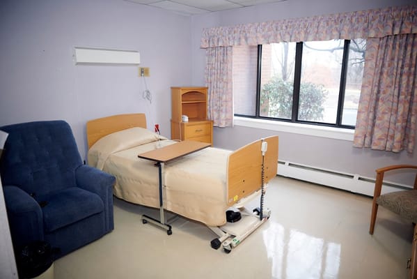 A cozy single bedroom featuring a hospital bed and a chair