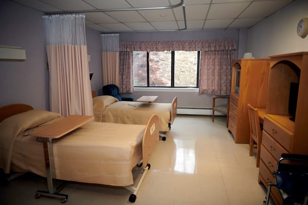 A bright bedroom with two hospital beds and furnishings.