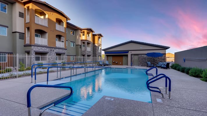 Outdoor pool area with lounge chairs and sunset sky