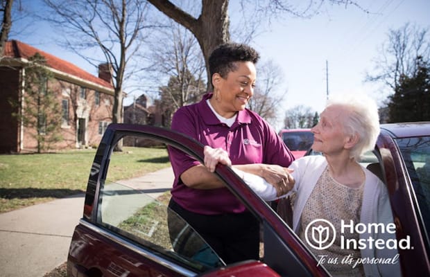 Caregiver assisting a senior woman from a vehicle