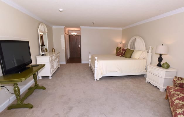 A cozy bedroom with a bed, dresser, and TV.
