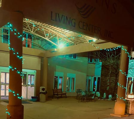 Night view of the entrance decorated with teal lights at Jenkin's Living Center.