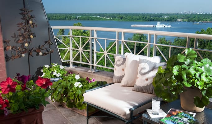 Outdoor balcony with seating and flowers overlooking water