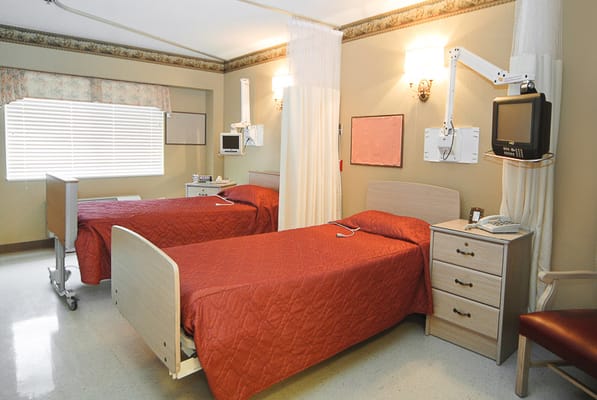 A patient room with two beds and modern amenities at Life Care Center of Longmont.