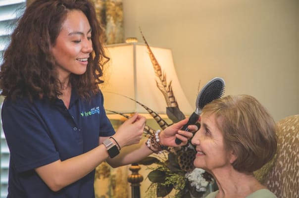 Staff member styling resident's hair in a common area
