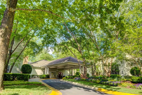 Welcoming entrance with lush landscaping and trees