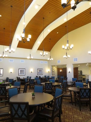 Dining area with round tables and chairs, featuring chandeliers and decorative art.