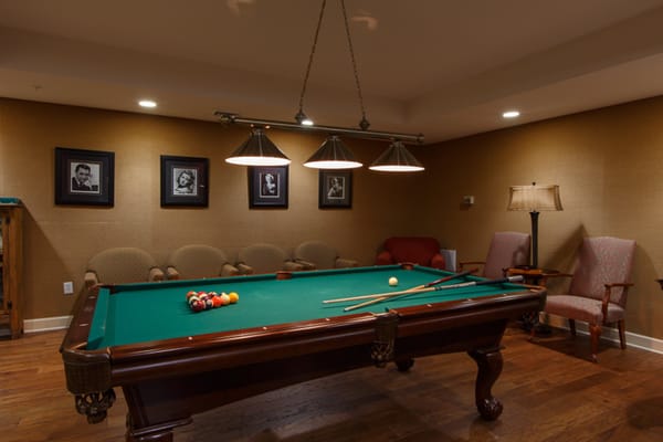 Interior view of the billiards room with a pool table and seating area.