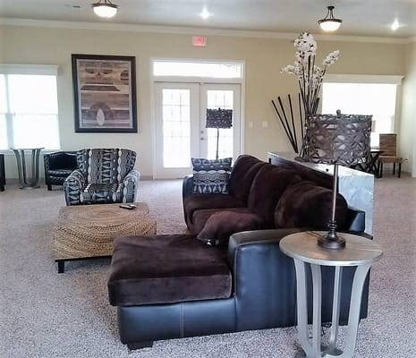 Cozy lounge area with a brown sectional sofa and decorative chairs.