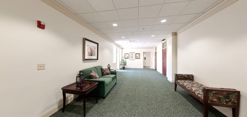 A hallway with seating and decorations in a senior living facility