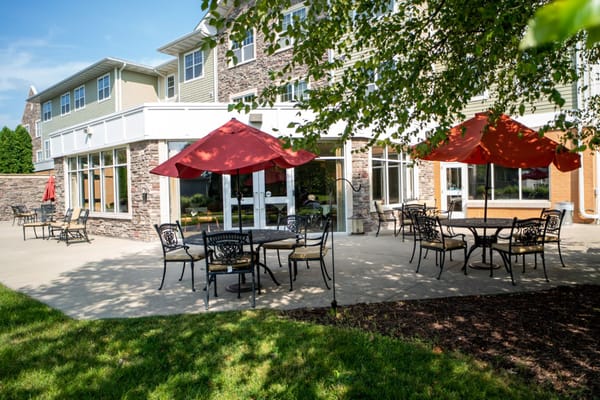 Outdoor seating area with tables, chairs, and red umbrellas.