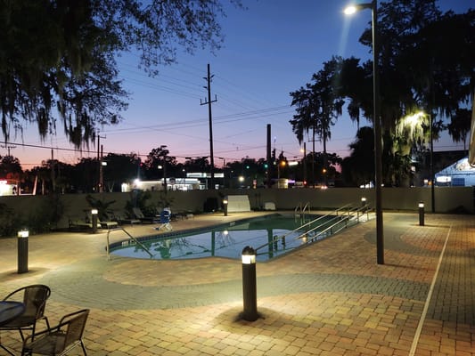 Illuminated pool area at night with lounge chairs