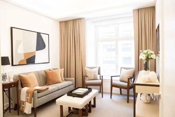 A well-decorated living room with a sofa, armchairs, and large windows.