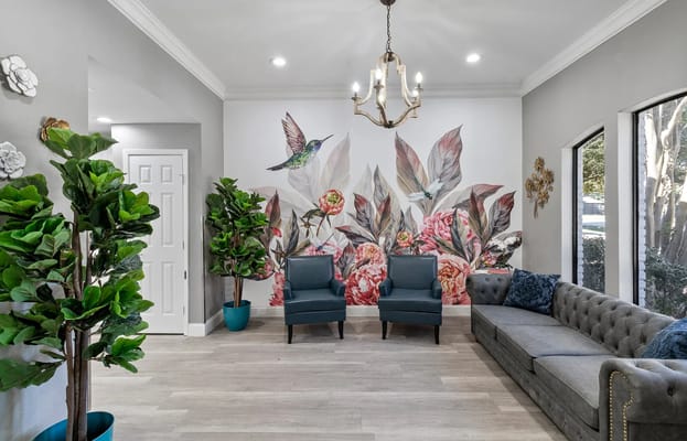 Bright lobby with floral mural, plants, and seating area