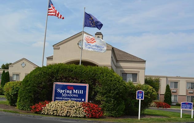 Entrance sign of Spring Mill Meadows with flags and landscaped area