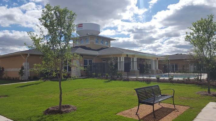 Springwood at Allen senior living facility exterior with landscaped lawn and swimming pool area.