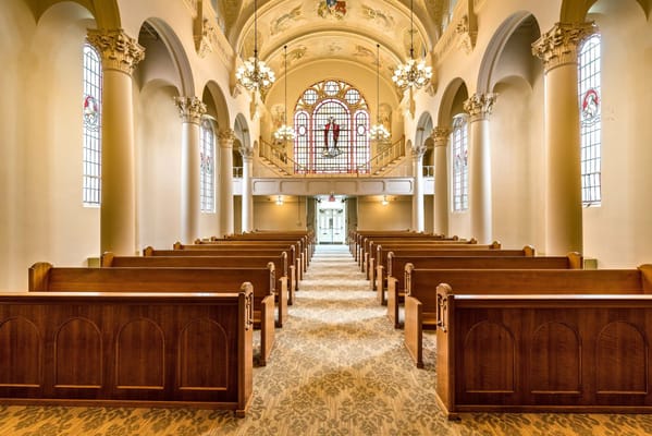Interior view of the chapel with wooden pews and stained glass windows