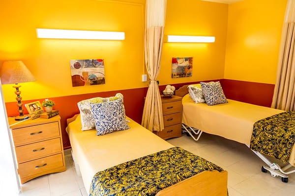 A brightly colored shared resident room with two beds
