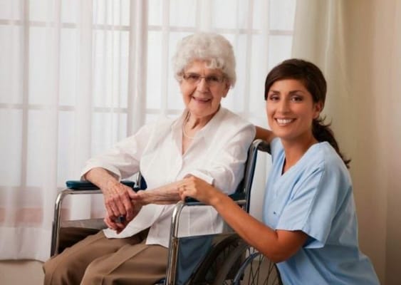 Smiling senior woman in a wheelchair with a caregiver