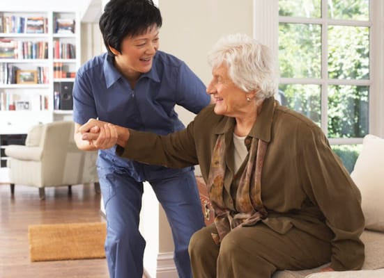 Caregiver helping a senior woman to stand up