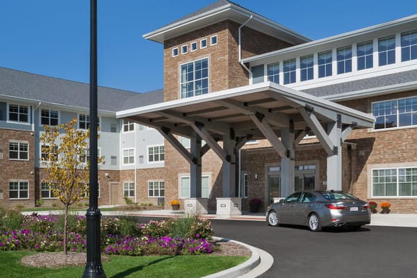 Front entrance of StoryPoint Schererville with flowers and a car