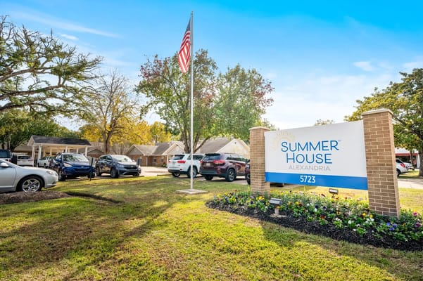 Sign for SummerHouse Alexandria with American flag and landscaped area