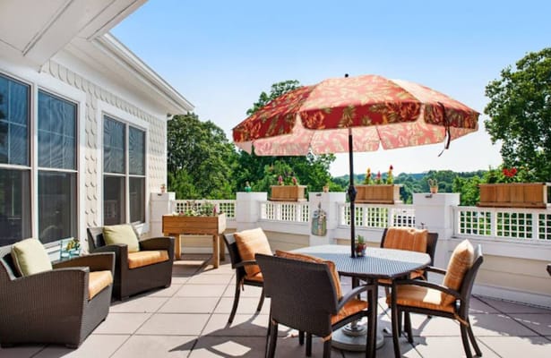 Patio with seating and umbrella at Sunrise of Hunter Mill