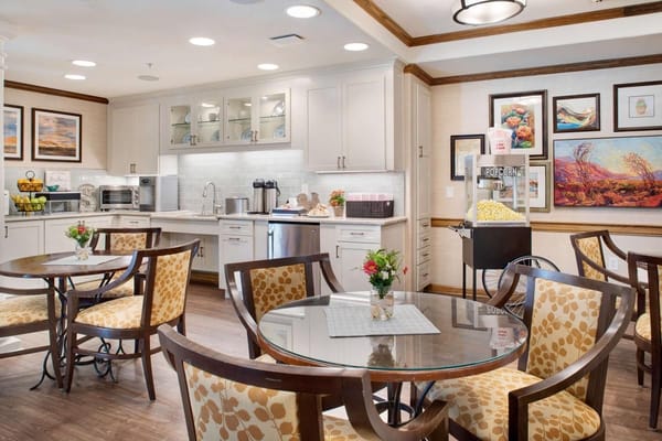 Bright dining area with tables and chairs in a senior living facility kitchen