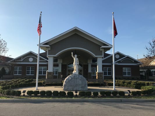 Front view of the Tennessee State Veterans' Home with flags and a statue.