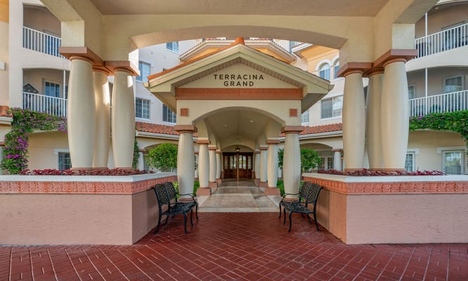 Entrance view of Terracina Grand senior living facility with benches and landscaped areas
