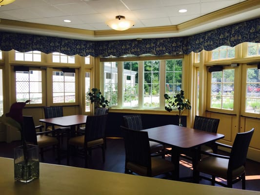 Bright dining area with large windows and tables at The Ambassador of Scarsdale.