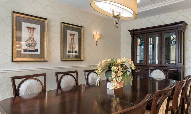 Dining room with a long wooden table, floral centerpiece, and framed artwork