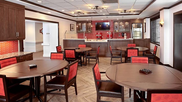 Bright dining room with round tables and red chairs