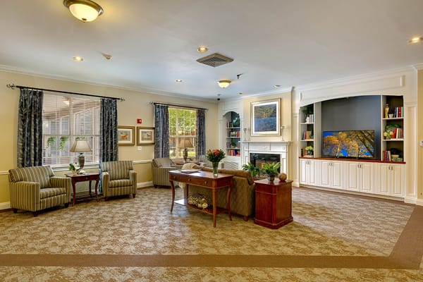 A spacious living room featuring comfortable striped chairs, a coffee table, and decorative shelving.